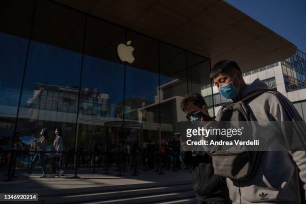 People watch their phones as they walk in front of an Apple store on October 16, 2021 in Beijing, China. According to an action plan released on...