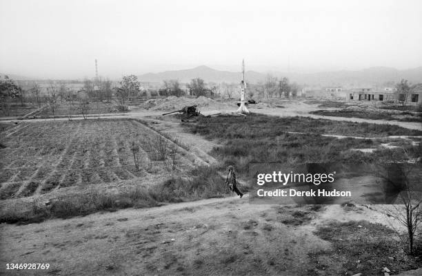 View across a field on with sits an artillery gun and a missile, on the outskirts of Kabul, Kabul Province, Afghanistan, October 2001. At bottom, an...