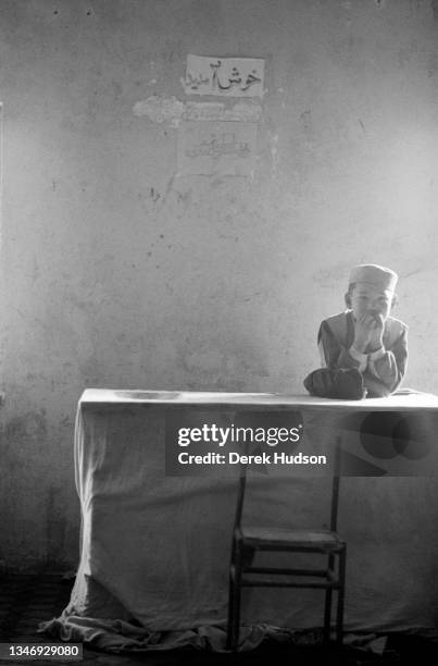 Portrait of a boy as he leans on a table in an orphanage on the outskirts of Kabul, Kabul Province, Afghanistan, October 2001.