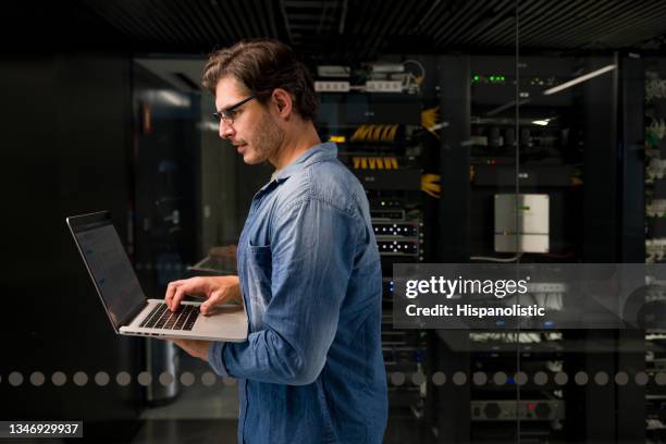 hacker trying to get into a network server at an office using his laptop computer - computer hardware engineer stock pictures, royalty-free photos & images