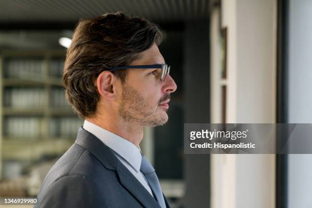 successful business man looking through the window of his office - male portrait suit and tie 40 year old stock pictures, royalty-free photos & images
