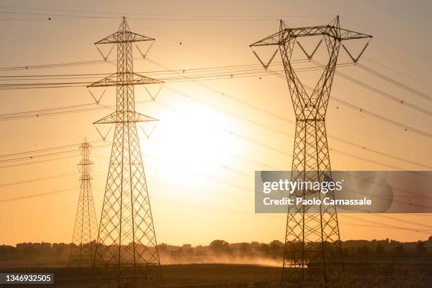 electricity pylons with sun on the back - electricity stockfoto's en -beelden