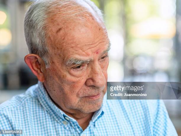 echte menschen - real life - älterer hispanischer mann, der nach unten schaut - hispanic senior face stock-fotos und bilder