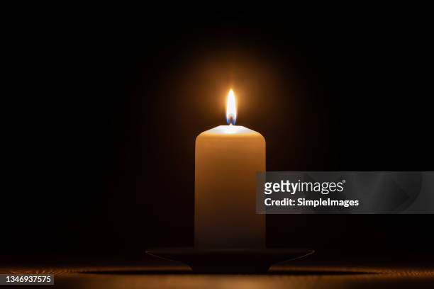 the wax candle glows in the dark. - mourning candles stock pictures, royalty-free photos & images