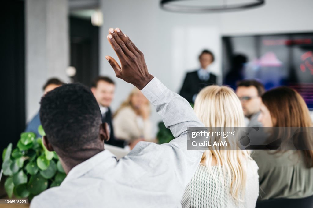 Young businessman raising his hand at a meeting