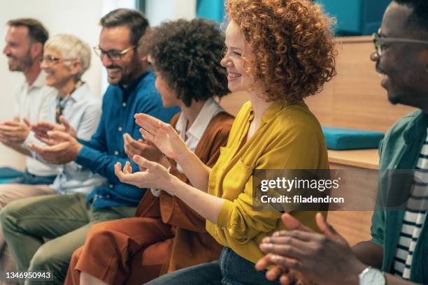 group of businesspeople sitting in a line and applauding - award stock pictures, royalty-free photos & images