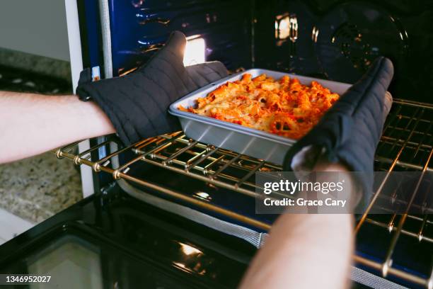 man removes pasta dish from oven - oven stock pictures, royalty-free photos & images