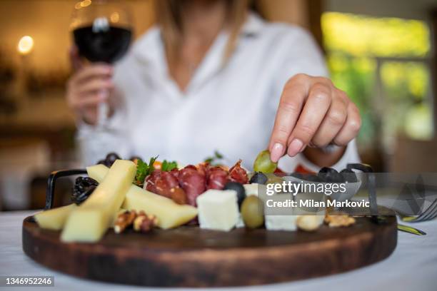 an elegant young woman having lunch in a cozy restaurant - cheese and wine bildbanksfoton och bilder
