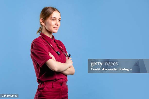 attraktiver kaukasischer fachsanitäter mit stethoskop in roter medizinischer notfalluniform. konzeptfoto im studio mit kopierraum für krankenwagen - arzthelferin stock-fotos und bilder