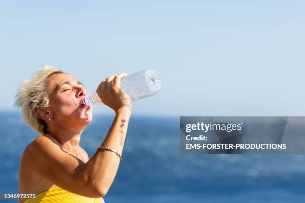 close-up of sportive woman drinking water from plastic pottle - heatwave 個照片及圖片檔