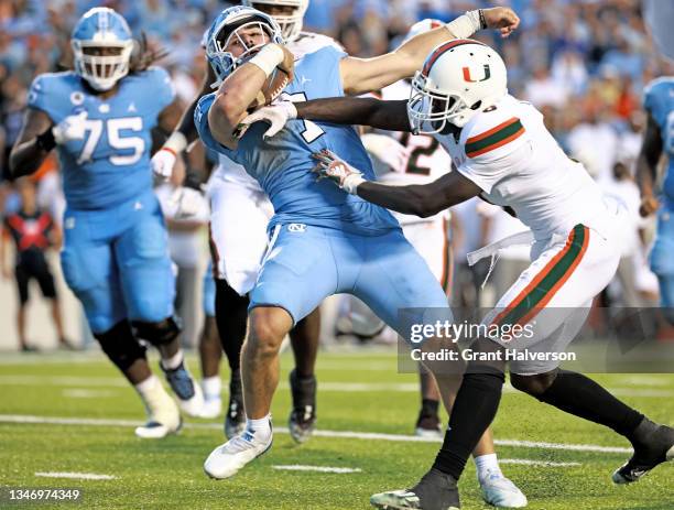 Sam Howell of the North Carolina Tar Heels collides with Sam Brooks Jr. #6 of the Miami Hurricanes as he runs for a touchdown during the second half...