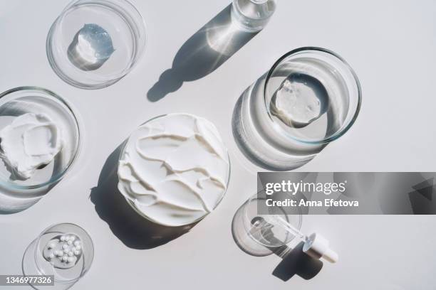 background made with many petri dishes with different cosmetics and a glass bottle with a face serum and a pipette on gray background. concept of cosmetics laboratory researches. photography in flat lay style - cosmetic texture photos et images de collection