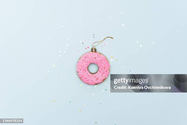 christmas bauble decoration made of pink doughnut on blue background. minimal concept. - funny christmas stock pictures, royalty-free photos & images