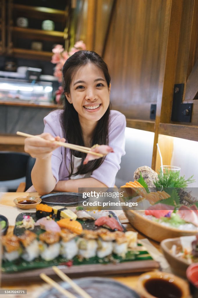 Asian female using mobile phone record video to social media before eating Set premium luxury Sushi,Shasimi,Maguro Nigiri,Sake Nigiri,Ikura Gukan,Toro,Anago,Hotate Nigiri,Tamagoyaki,Aji in japan