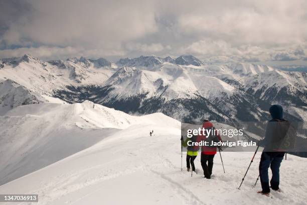 hikers use walking poles during a hike with panoramic view on polish and slovakia tatra mountains covered with snow in poland. - tatra stockfoto's en -beelden