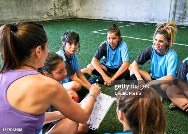 mädchen hören weiblicher trainerin auf sportplatz zu - talent team coaching stock-fotos und bilder