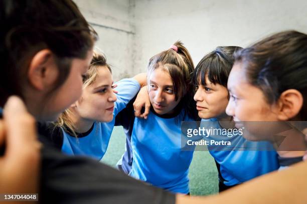 Girls team in huddle discussing game plan at sports court