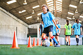 Confident female soccer player practicing skills at court