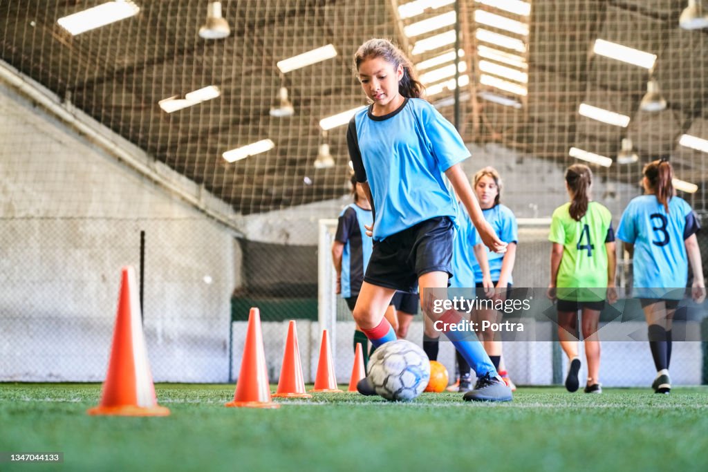 Confident female soccer player practicing skills at court
