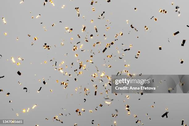 golden festive confetti falling over gray background. golden festive confetti falling over pink background. concept of celebrating new year's coming or birthday. - confetti photos et images de collection