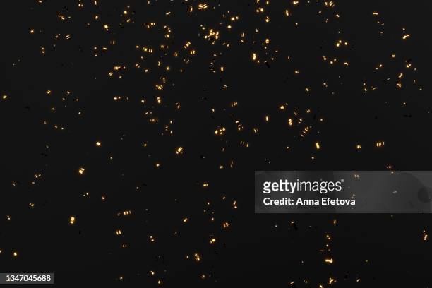 glittering golden confetti on black isolated background. christmas and new year concept in trendy festive golden color. - confetti photos et images de collection