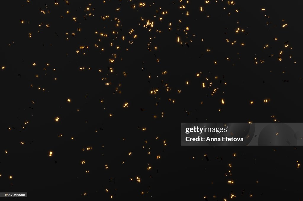 Glittering golden confetti on black isolated background. Christmas and New Year concept in trendy festive golden color.