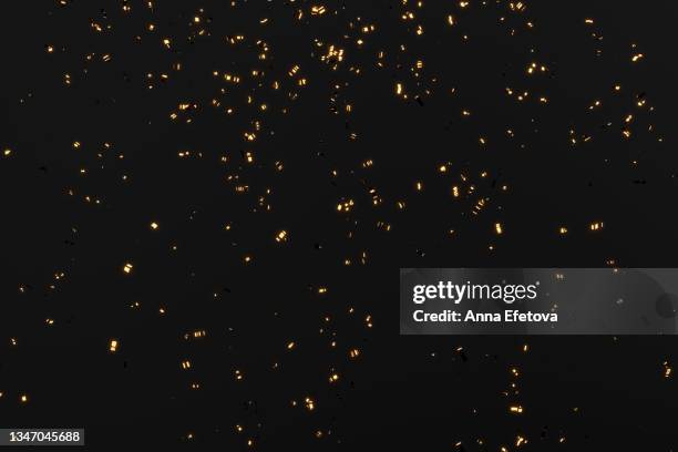 glittering golden confetti on black isolated background. christmas and new year concept in trendy festive golden color. - confeti bildbanksfoton och bilder