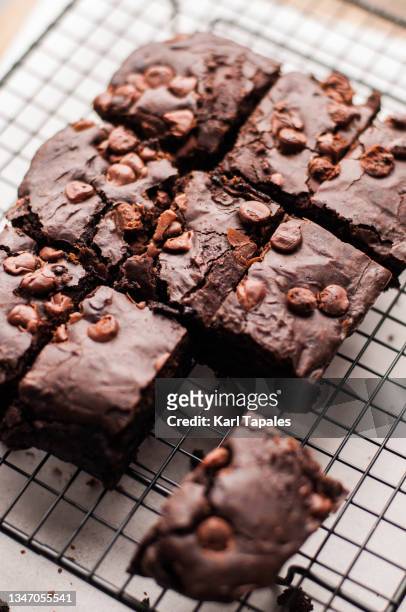 freshly baked chocolate brownies resting on a wire rack - brownie stockfoto's en -beelden
