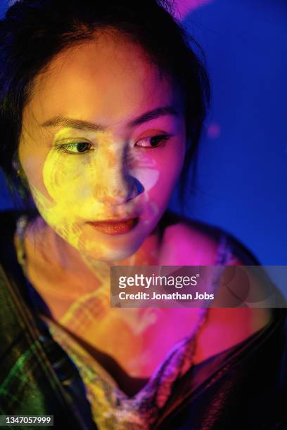 a stylish woman in a black leather jacket is illuminated by colorful neon lights - neon fluorescent hair stock pictures, royalty-free photos & images