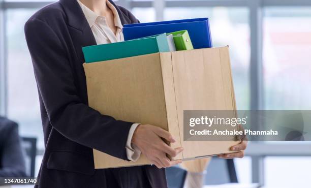 business concept:   an unemployed with her cardboard box walking out of the work office. - quitting a job stock-fotos und bilder