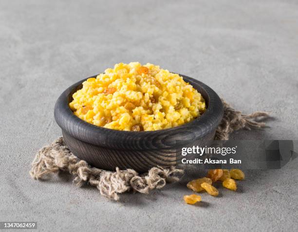 russian traditional autumn dish. millet porridge with pumpkin and raisins in a wooden bowl on a linen napkin on a light gray background in rustic style - miglio foto e immagini stock
