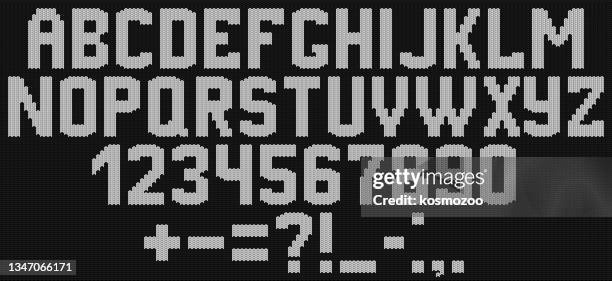 alphabet knitted on a black background with white yarn - embroidery letters stock illustrations