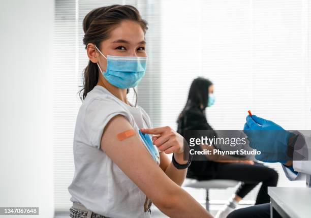 girl showing her covid 19 vaccine bandage - lining up for vaccine stock pictures, royalty-free photos & images