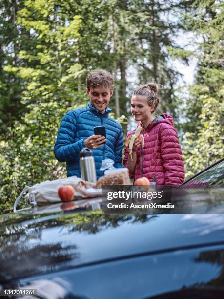 young couple enjoy picnic on car hood, before hike - banana phone stock pictures, royalty-free photos & images