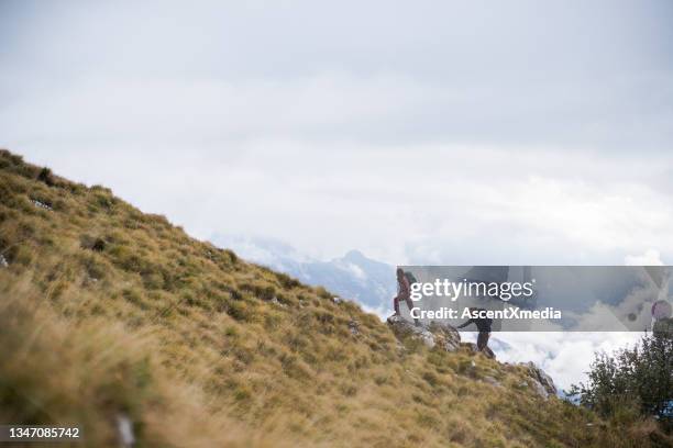 hiking couple follow trail up grassy mountain ridge - challenger tour 2 stock pictures, royalty-free photos & images