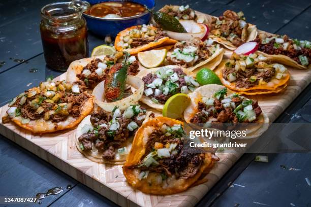 köstliche auswahl an authentischen straßen-tacos auf einer holzplatte mit limettenscheiben, rindfleisch und chili diarbo sauce - meat platter stock-fotos und bilder