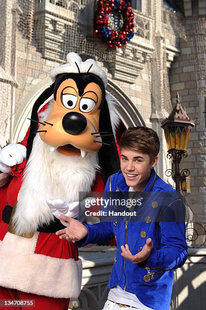 In this handout image provided by Disney Parks, Justin Bieber poses with Santa Goofy during a break while taping a performance segment for the...