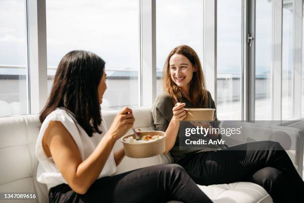 two business women eating healthy lunch at work - lunchpauze stockfoto's en -beelden