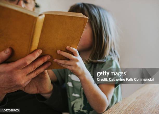 a father reads a book to his daughter - story book stock-fotos und bilder