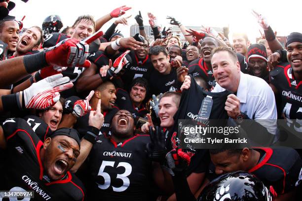Butch Jones coach of the Cincinnati Bearcats celebrates with his team after the Bearcats defeated the Connecticut Huskies 35-27 to claim their share...
