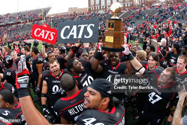 Rob Trigg of the Cincinnati Bearcats holds the the Big East Championship Trophy as he celebrates with fans and teammates after the Bearcats defeated...