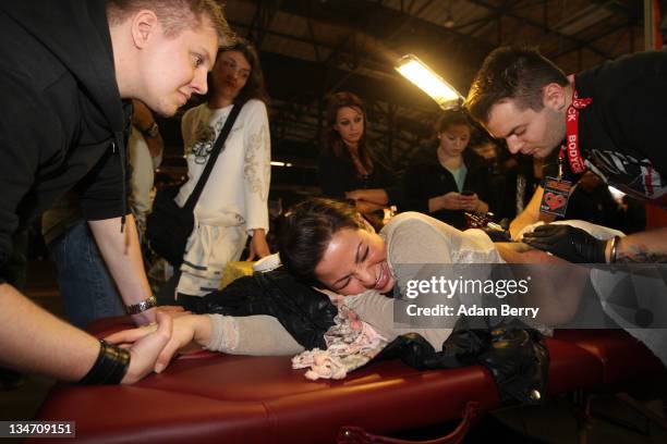 Customer grimaces in pain as she gets a tattoo on her back at the 21st International Tattoo Convention Berlin on December 3, 2011 in Berlin, Germany....