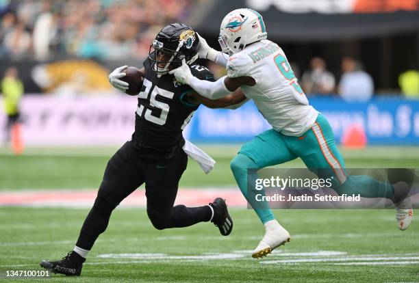 Noah Igbinoghene of the Miami Dolphins tackles James Robinson of the Jacksonville Jaguars during the NFL match between the Miami Dolphins and...