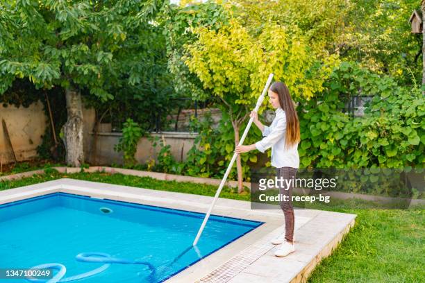 female pool cleaner cleaning pool with vacuum cleaner - swimming pool cleaning stock pictures, royalty-free photos & images