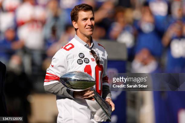 Former New York Giants quarterback Eli Manning walks onto the field carrying the Vince Lombardi Trophy during a ceremony honoring the 2011 Giants...