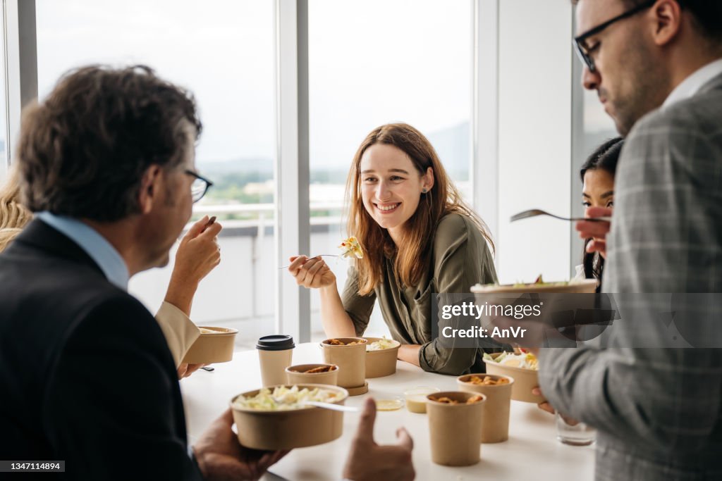 Lächelnde Frau, die das Mittagessen zum Mitnehmen bei der Arbeit genießt