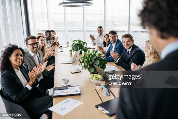 co-workers applauding their manager at a meeting - co presented stockfoto's en -beelden