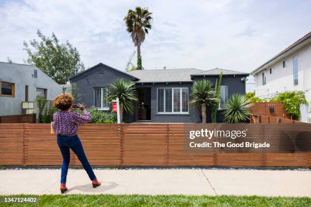 mature saleswoman photographing house through smart phone while working - house fence stock pictures, royalty-free photos & images