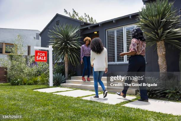 full length of saleswoman greeting female customers while standing outside house - visita de inmuebles en venta fotografías e imágenes de stock