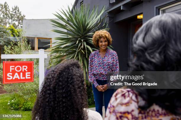 smiling female real estate agent greeting customers outside house - real people lifestyle and family foto e immagini stock